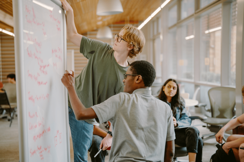 Students work on a problem together using a whiteboard